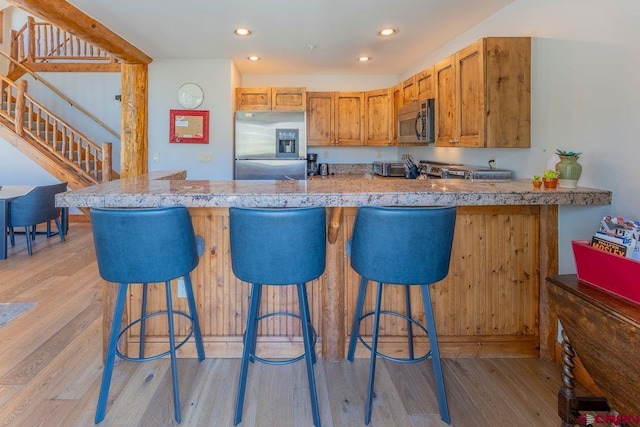 kitchen featuring stainless steel appliances, recessed lighting, a breakfast bar area, and light wood-style floors