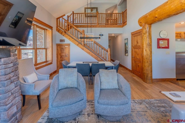 living area featuring stairway, wood finished floors, baseboards, and high vaulted ceiling