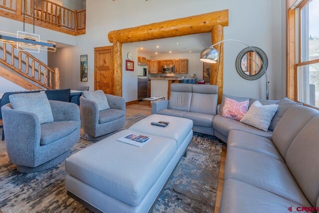 living area with stairs, a towering ceiling, and wood finished floors