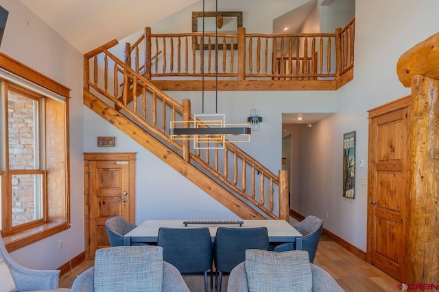 dining area with a towering ceiling, stairs, and baseboards