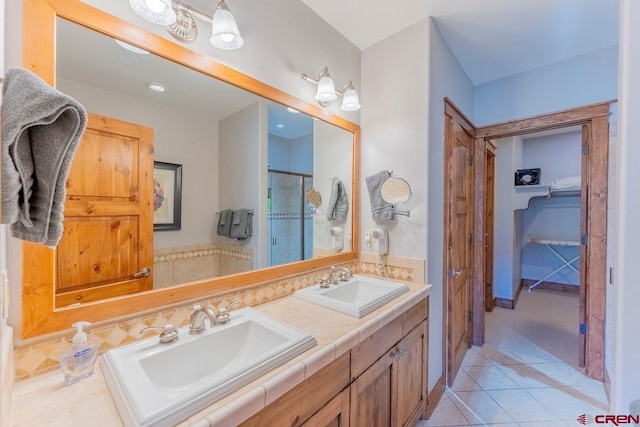 bathroom with double vanity, tile patterned floors, a stall shower, and a sink