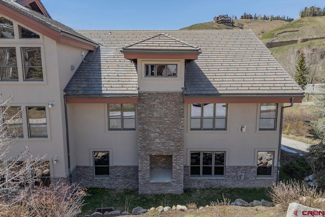 rear view of house with stone siding and stucco siding