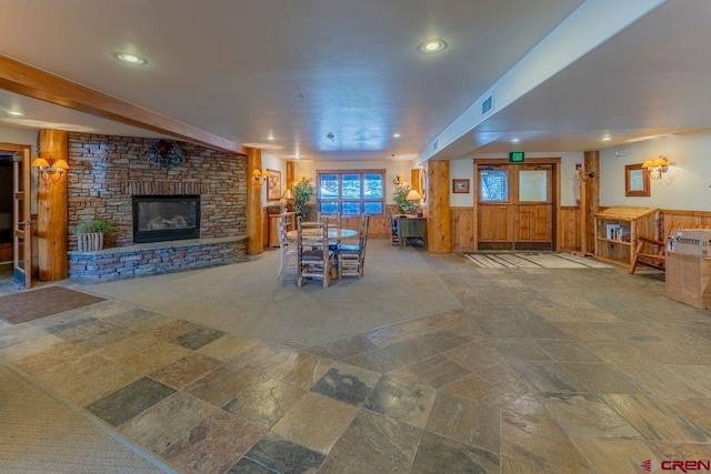 dining space featuring recessed lighting, a stone fireplace, stone finish flooring, wainscoting, and visible vents