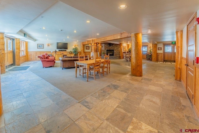 dining room with recessed lighting, stone finish flooring, wainscoting, wood walls, and a fireplace