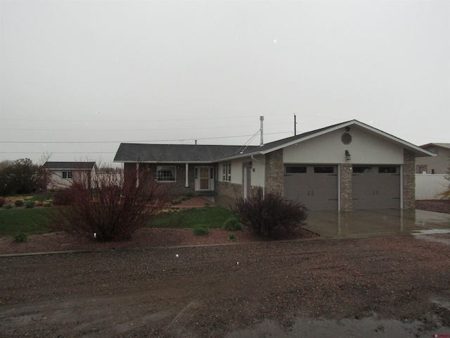 ranch-style home featuring concrete driveway, a garage, and stone siding