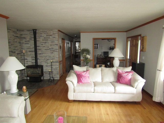 living area with a wood stove, wood finished floors, and ornamental molding