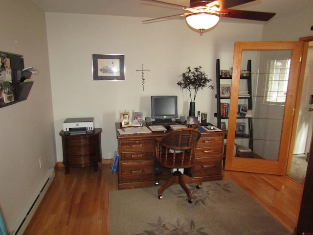 office space featuring ceiling fan, wood finished floors, baseboards, and a baseboard heating unit