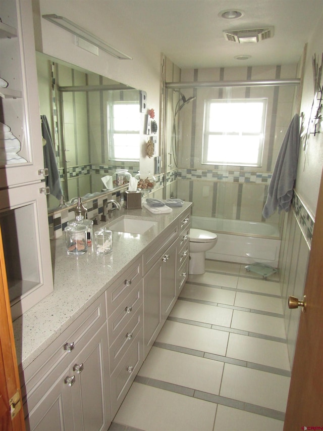 bathroom with toilet, enclosed tub / shower combo, visible vents, tile patterned flooring, and vanity