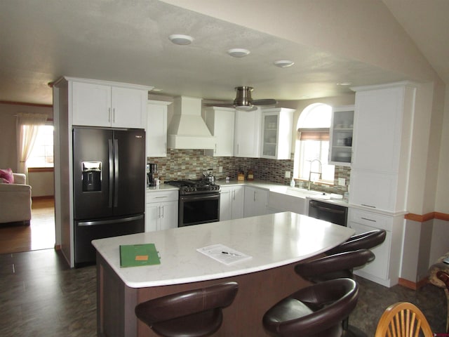 kitchen featuring black fridge with ice dispenser, a breakfast bar area, dishwasher, custom exhaust hood, and gas range