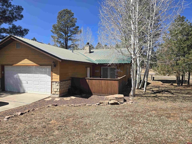 369 Beaver Cir, Pagosa Springs, CO 81147 - view of side of property featuring a chimney, a garage, concrete driveway, and metal roof