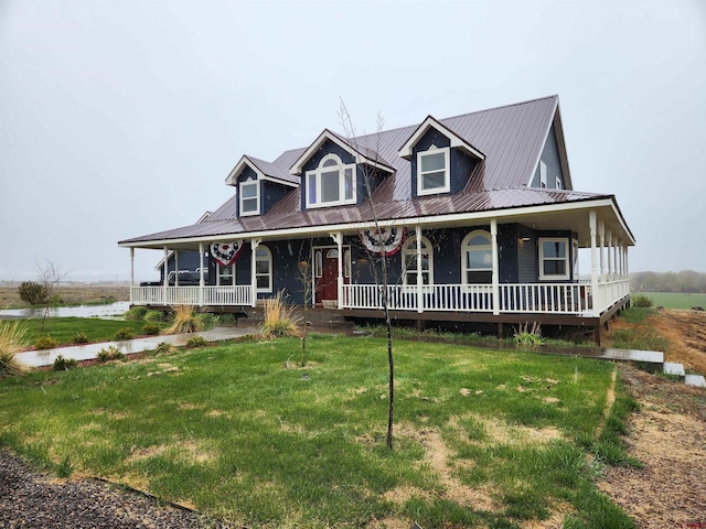 country-style home with a porch, a water view, metal roof, and a front lawn