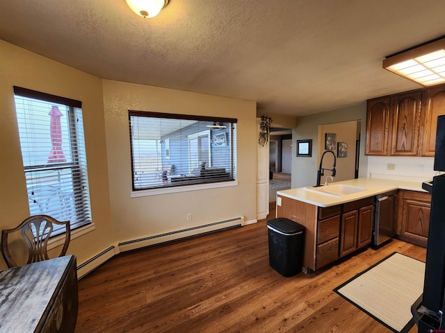 kitchen with a textured ceiling, dishwasher, a sink, a peninsula, and light wood-style floors