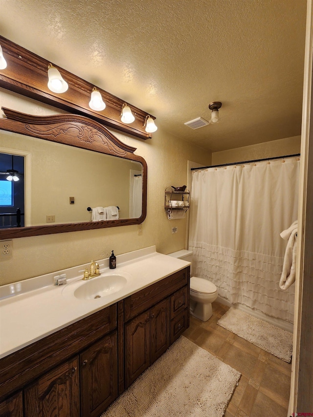 bathroom featuring vanity, toilet, a textured ceiling, and visible vents