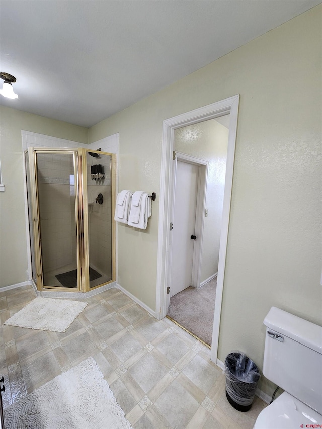 bathroom with toilet, baseboards, and a shower stall