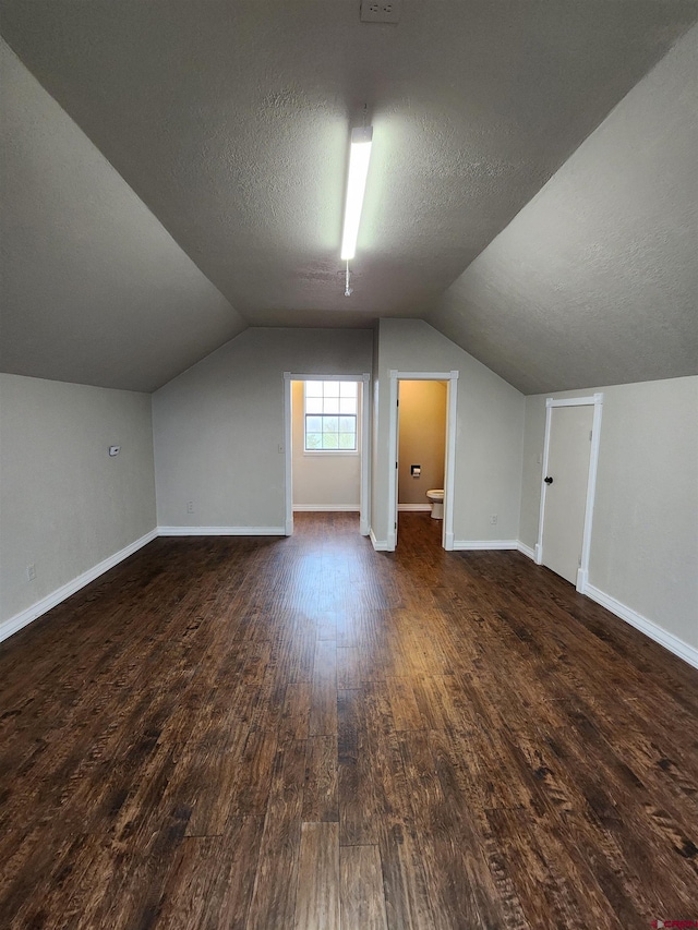 bonus room featuring dark wood-style flooring, a textured ceiling, and baseboards