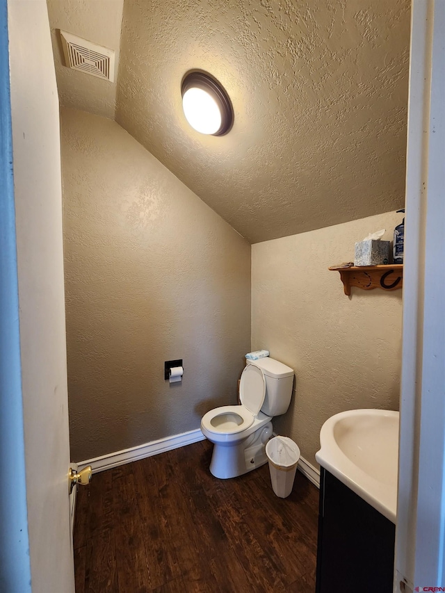 bathroom featuring vaulted ceiling, a textured ceiling, toilet, and visible vents