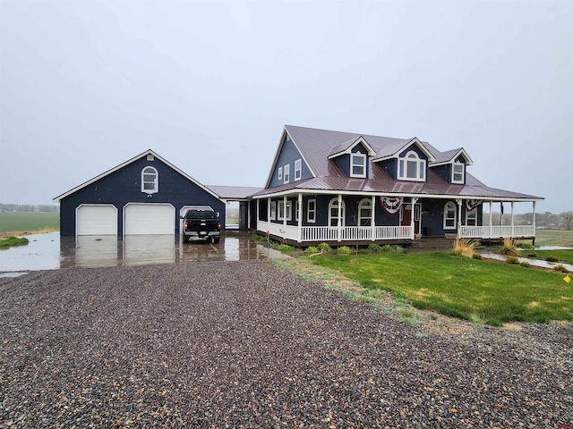 farmhouse inspired home with covered porch, an outdoor structure, driveway, metal roof, and a front lawn
