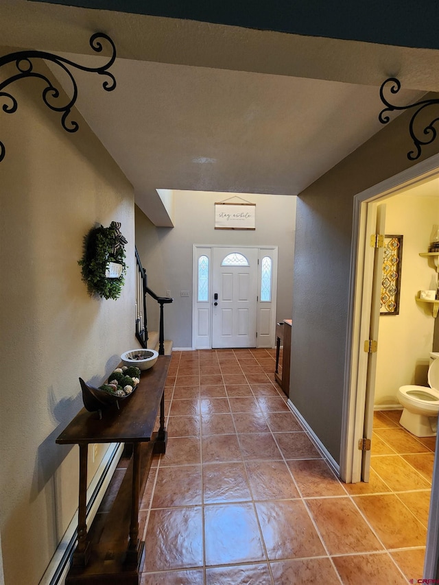 foyer entrance featuring stairway, tile patterned flooring, and baseboards