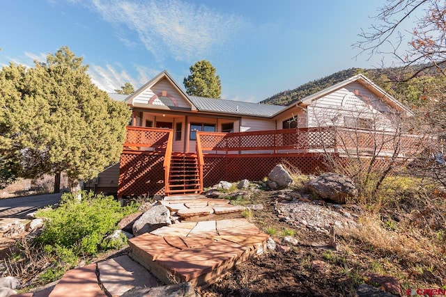 rear view of house with metal roof and stairs