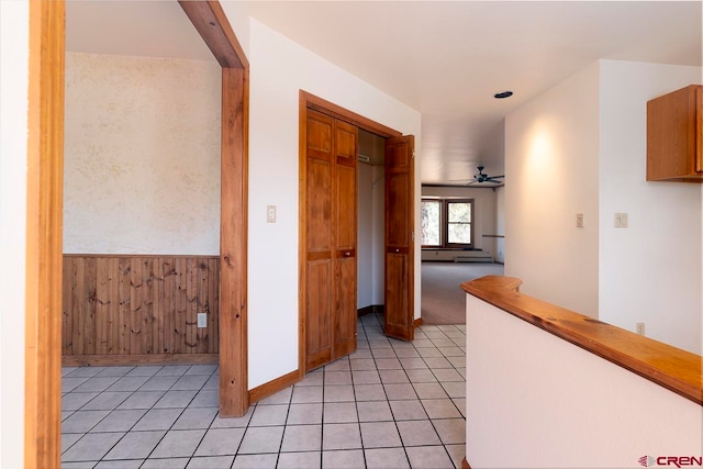 corridor with wainscoting, a baseboard radiator, baseboards, and light tile patterned floors