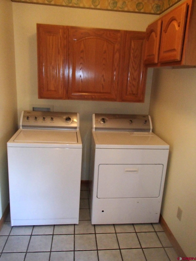 laundry area with cabinet space, washing machine and clothes dryer, baseboards, and light tile patterned flooring