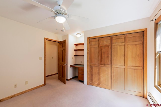 unfurnished bedroom featuring a closet, a baseboard heating unit, baseboards, ceiling fan, and light carpet