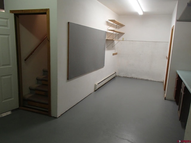 basement featuring stairs and a baseboard heating unit