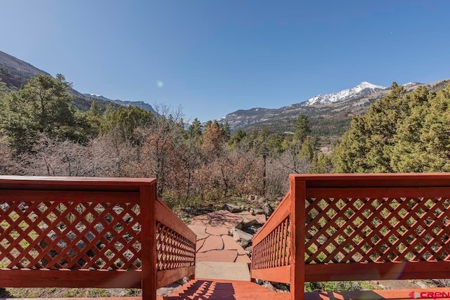 wooden deck with a forest view and a mountain view