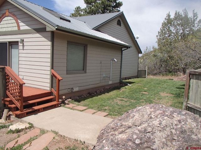view of side of home with metal roof and a lawn