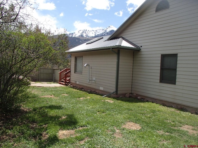 view of side of home featuring a mountain view, a yard, and fence