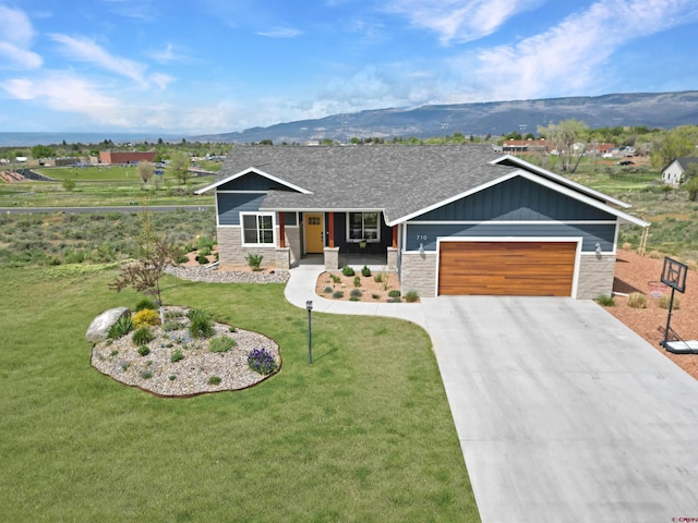 710 SE Pine St, Cedaredge, CO 81413 - ranch-style house with stone siding, an attached garage, driveway, a mountain view, and a front lawn