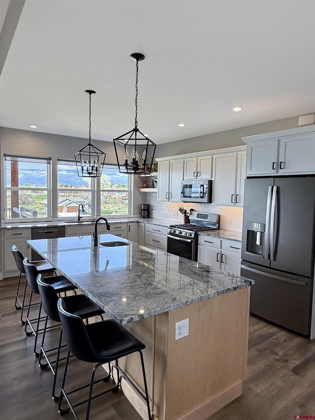 710 SE Pine St, Cedaredge, CO 81413 - kitchen with stainless steel appliances, a sink, a kitchen island with sink, decorative backsplash, and white cabinetry