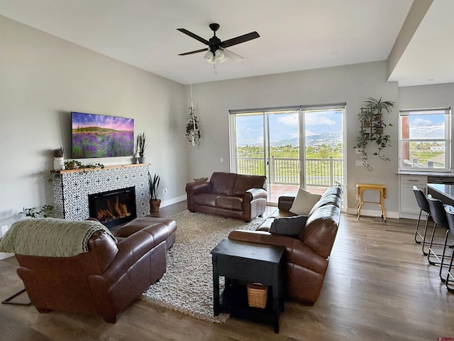 710 SE Pine St, Cedaredge, CO 81413 - living room featuring wood finished floors, ceiling fan, a tile fireplace, and baseboards