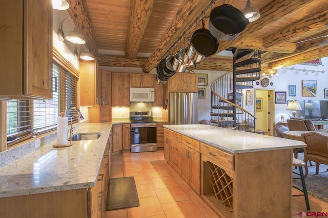 kitchen with appliances with stainless steel finishes, a sink, beamed ceiling, wood ceiling, and a breakfast bar area