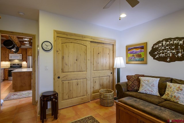 living area with light tile patterned flooring and a ceiling fan