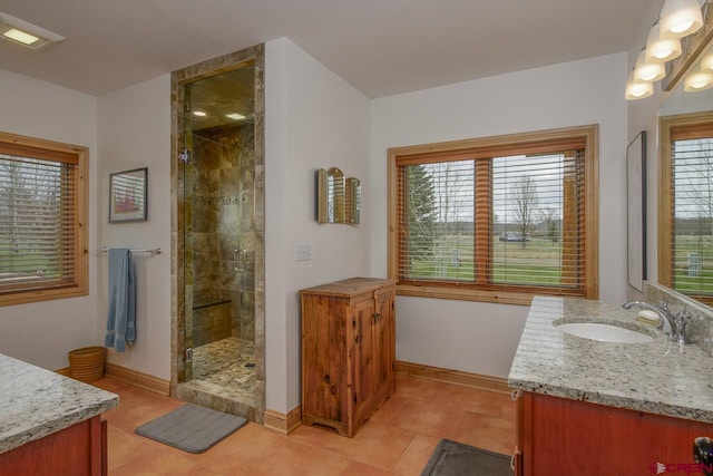 full bath featuring a shower stall, vanity, baseboards, and tile patterned flooring
