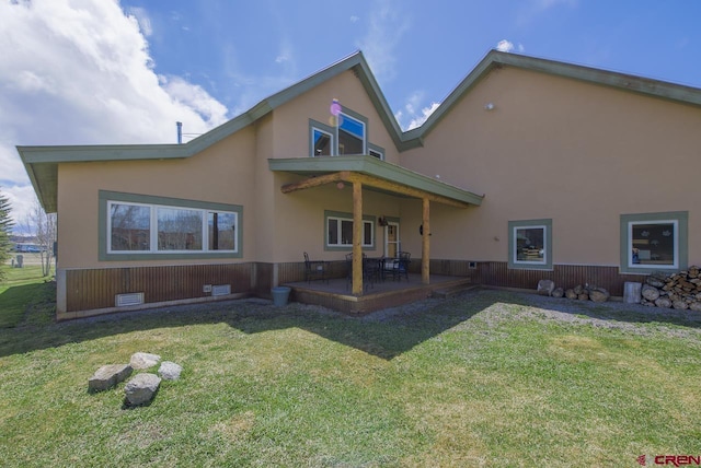 back of property with a patio area, a lawn, and stucco siding