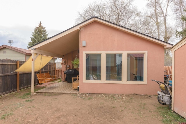 back of property with a deck, fence, and stucco siding