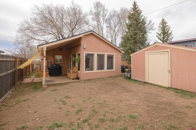 rear view of property with a fenced backyard, a storage shed, an outdoor structure, and a deck