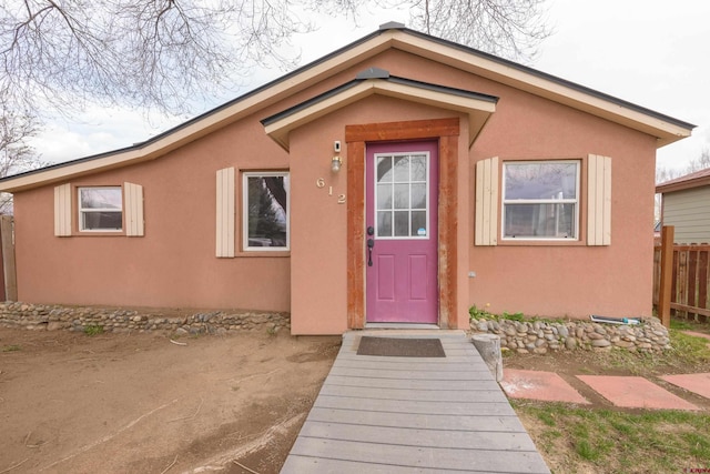 entrance to property with stucco siding and fence