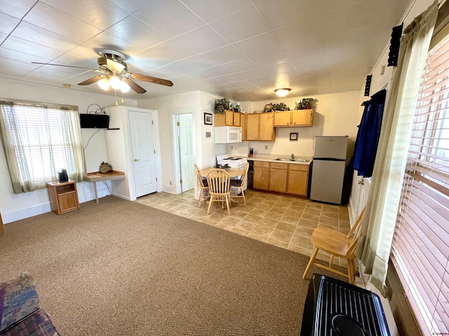 kitchen with white appliances, a sink, ceiling fan, and baseboards