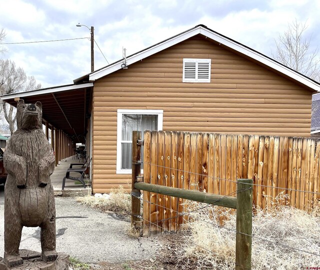 view of side of property featuring log veneer siding and fence