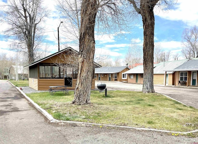 view of front of property featuring log veneer siding, a front yard, and a residential view