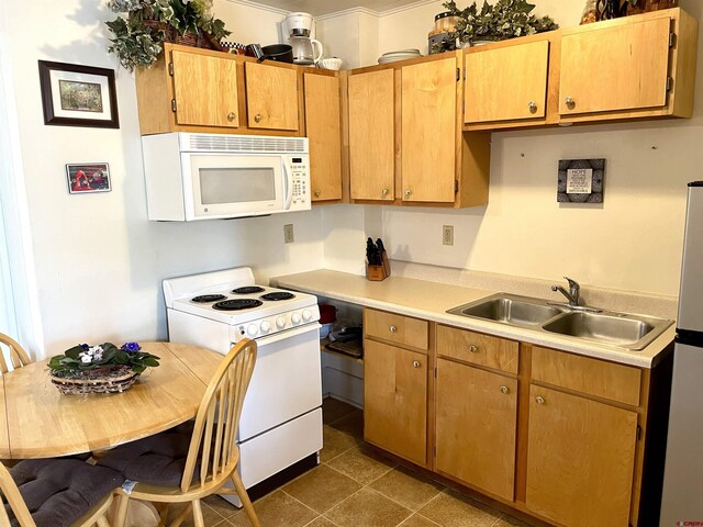 kitchen featuring white appliances, a sink, light countertops, and dark tile patterned floors