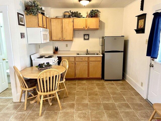 kitchen featuring white appliances, a sink, light countertops, and baseboards