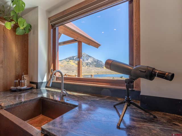 kitchen view of a sink, a mountain view, and dark stone countertops
