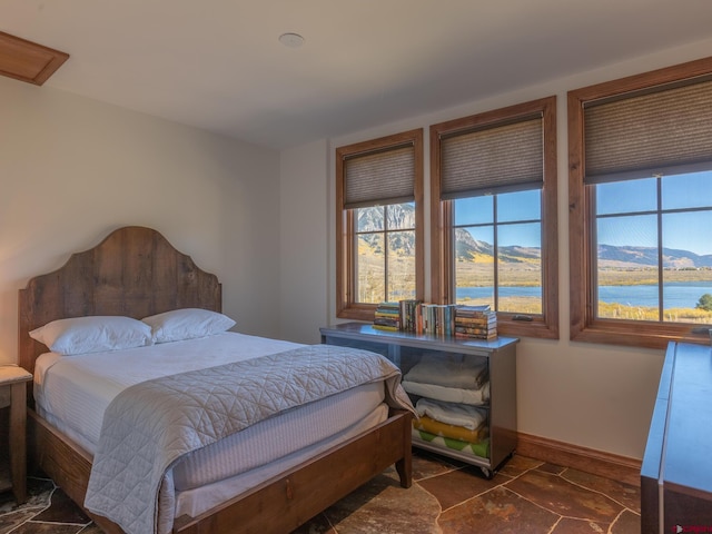 bedroom featuring baseboards and a water and mountain view