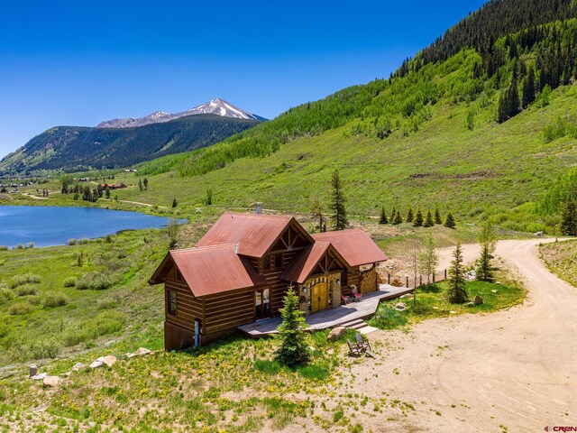 mountain view featuring a large body of water and a heavily wooded area