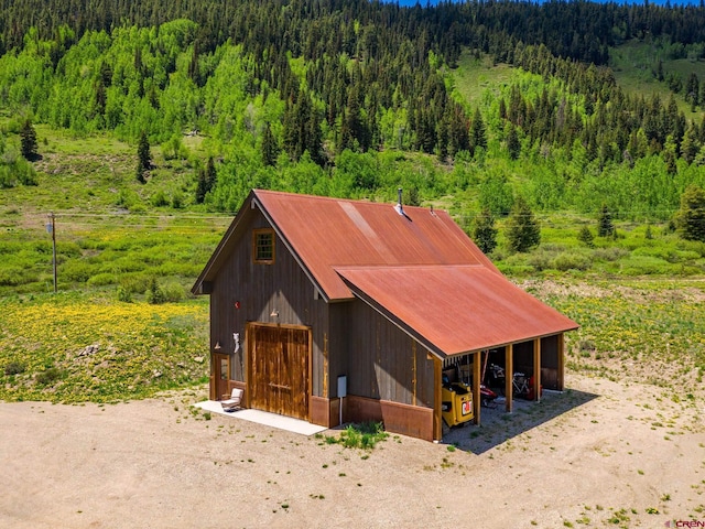 1482 Peanut Lake Rd, Crested Butte, CO 81224 - view of front facade with a view of trees, an outdoor structure, an outbuilding, and a garage