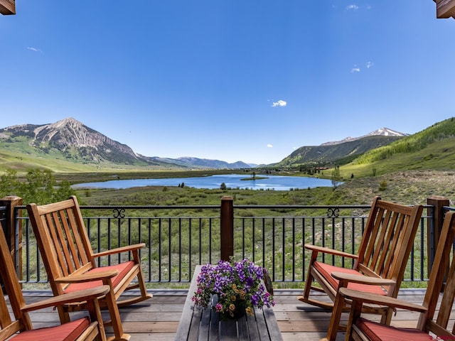 wooden deck with a water and mountain view